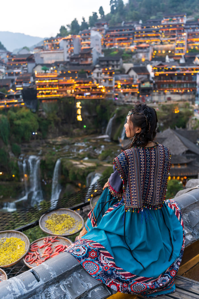 Mujer china viendo el atardecer, al fondo la ciudad lijiang